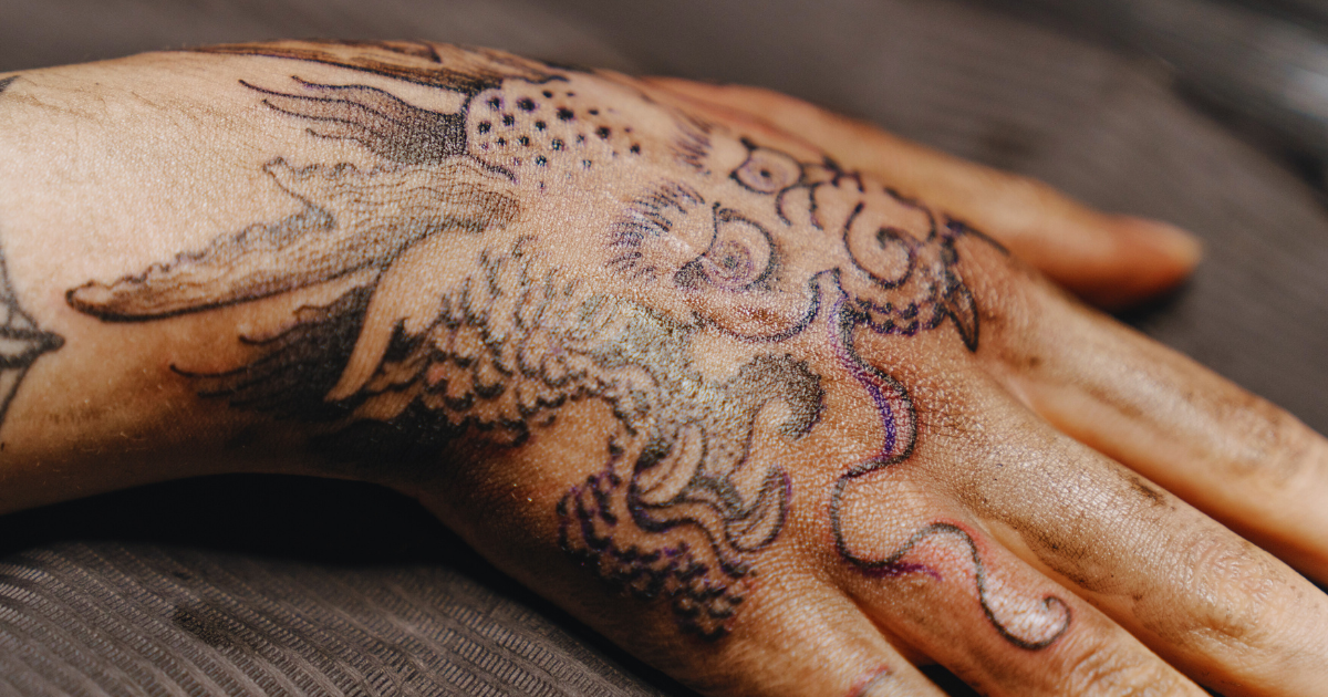 A detailed view of a hand adorned with a dragon tattoo, showcasing vibrant ink and artistry.